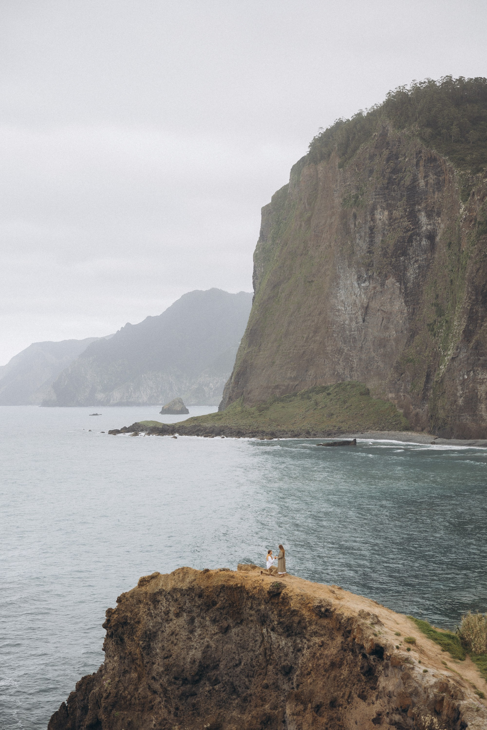 Surprise proposal in Madeira — romantic engagement captured on cliffs with ocean views.