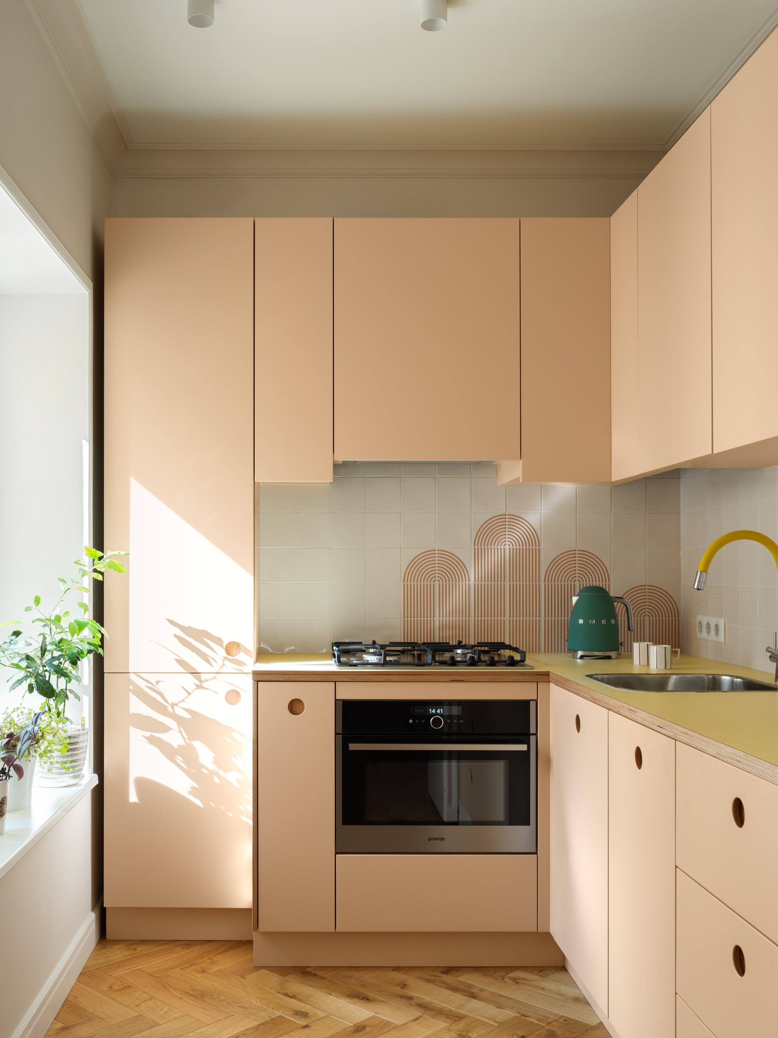 Персиковая кухня из фанеры с жёлтой столешницей и жёлтым смесителем.