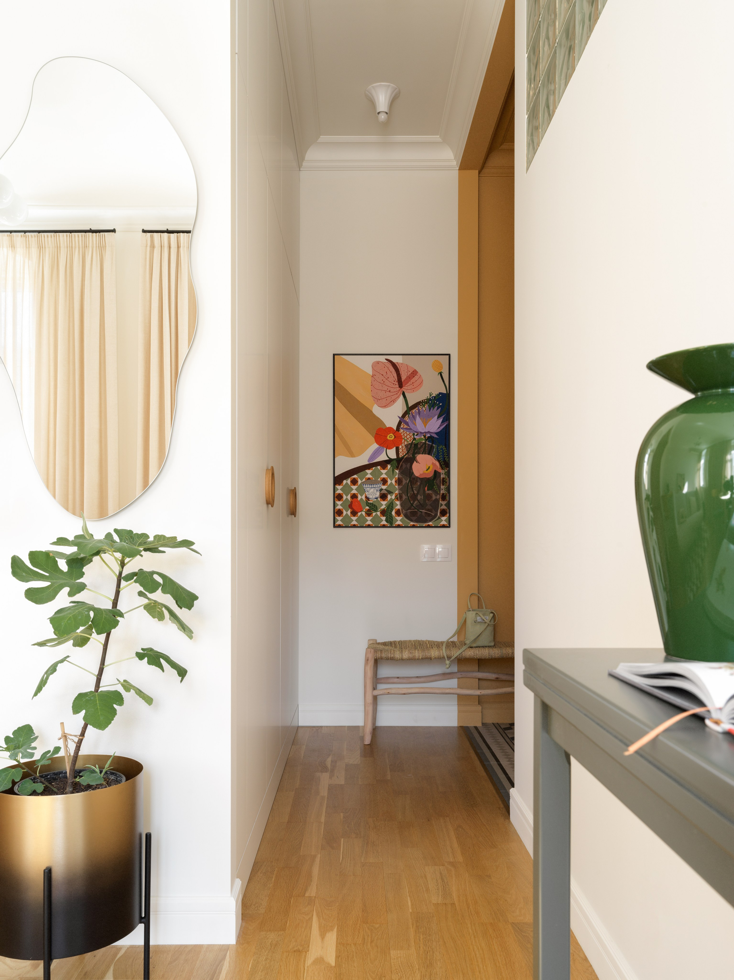 Прихожая с акцентной плиткой, деревянной скамейкой и овальным зеркалом.