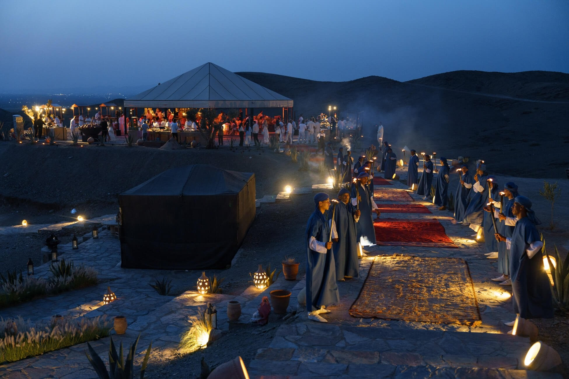 Evening view of desert wedding reception with torchlit walkway, Morocco