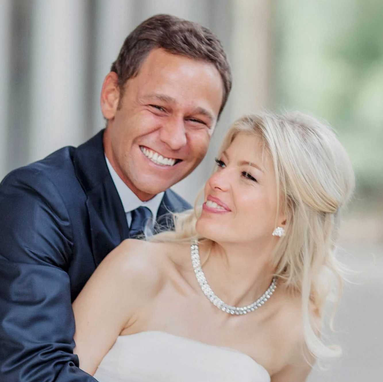 Smiling blonde-haired Swiss bride smiles lovingly towards her Italian groom as he looks towards the camera at a garden in Prague. 