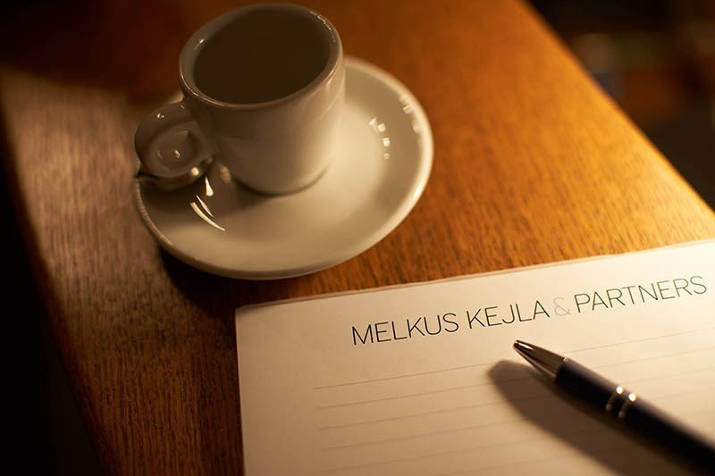 A branded notepad featuring a prominent Prague law firm and an espresso await.