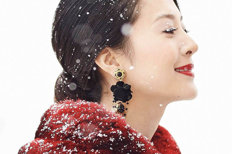 Close-up portrait of Helen in fine jewelry as snowflakes settle on her face in Prague.