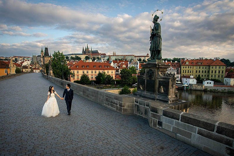 A silhouette of a couple embracing as they look across the Charles Bridge towards Prague Castle.