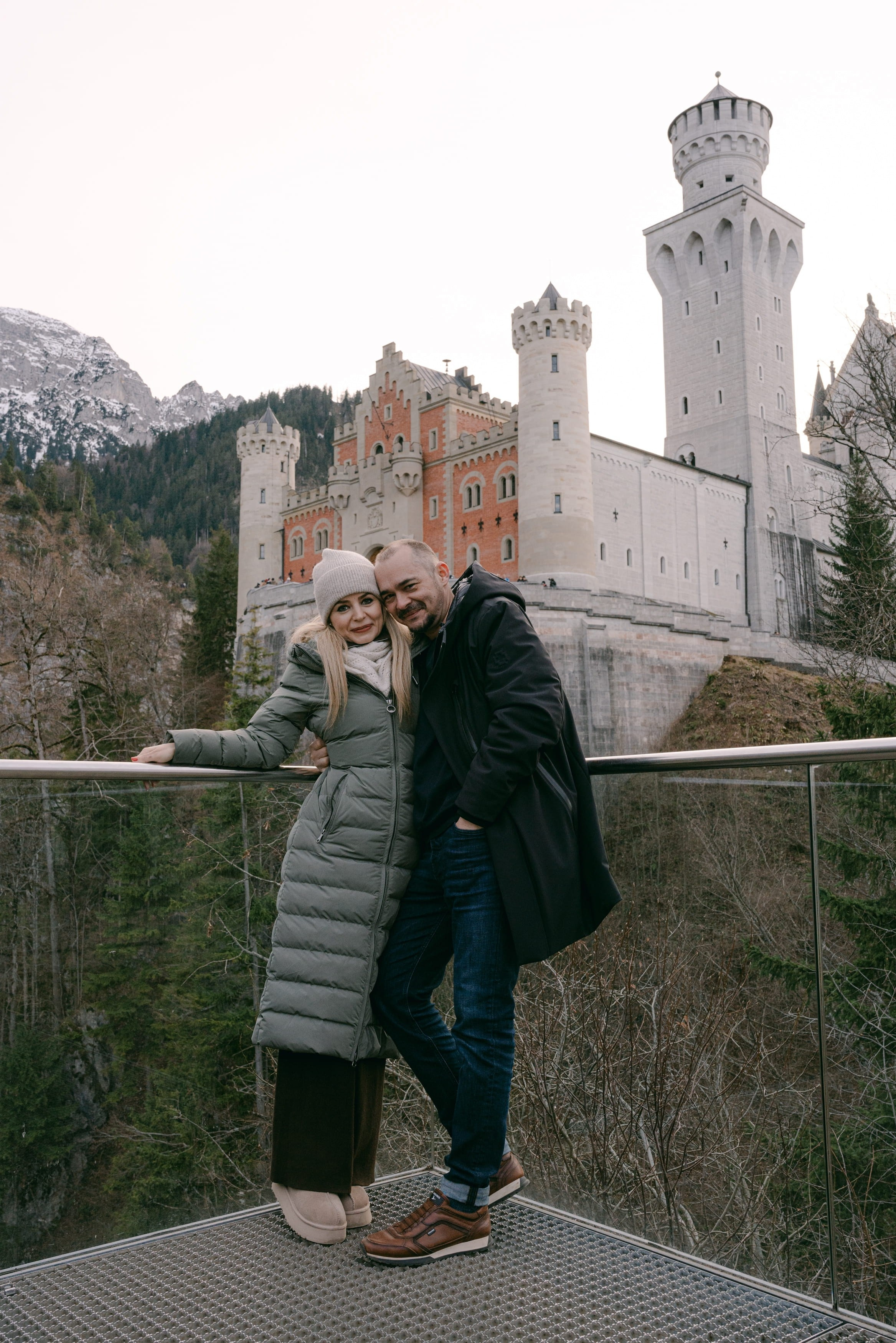 Couple photoshoot at Neuschwanstein Castle in Germany, full-length portrait on Marienbrücke bridge with the castle in the background