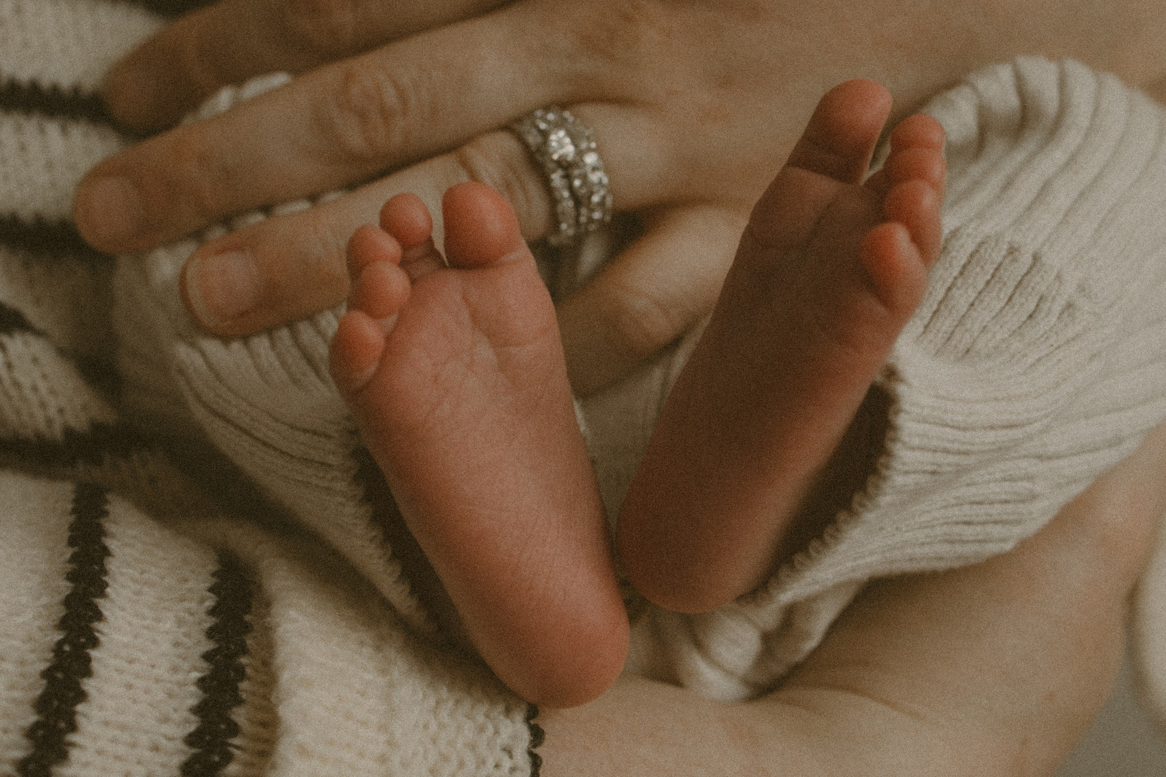 Mom gently cradling her baby’s tiny feet during an intimate in-home newborn session"