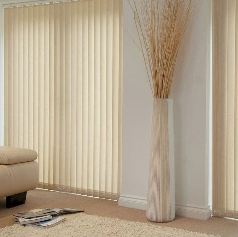 Часть комнаты с современным ремонтом и установленными на окнах вертикальных жалюзи светлого бежевого оттенка.