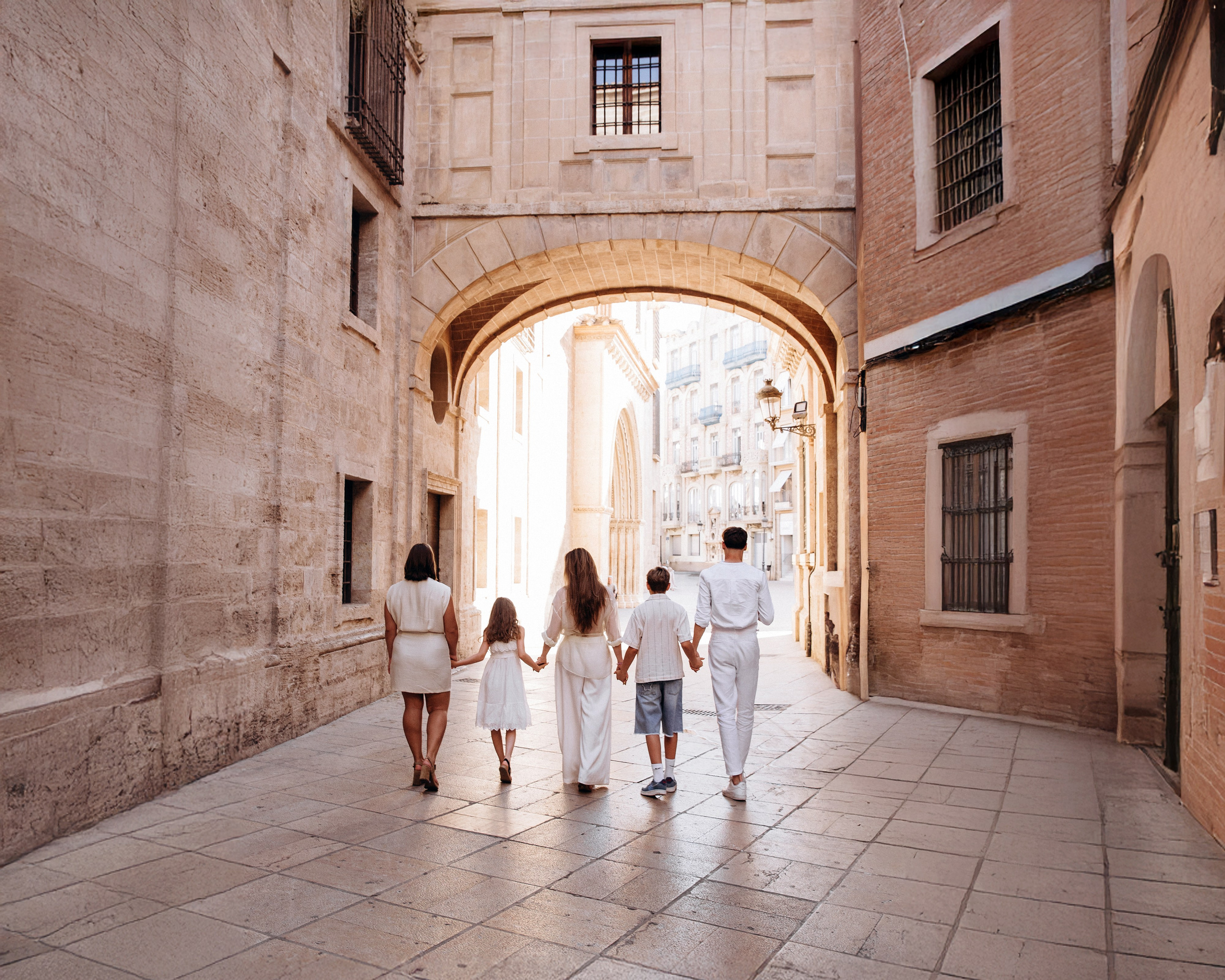 Сімейна фотосесія в Старому місті Валенсії, де узгоджена світла кольорова палітра одягу створює елегантний і позачасовий образ на тлі історичної архітектури.