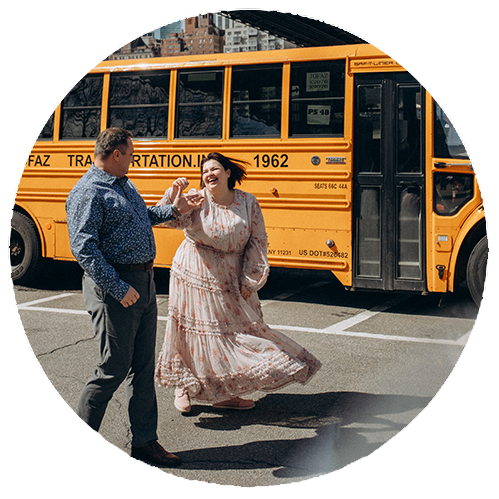 Romantic couple dancing in Dumbo, Brooklyn with Manhattan Bridge in the background — candid NYC engagement photo