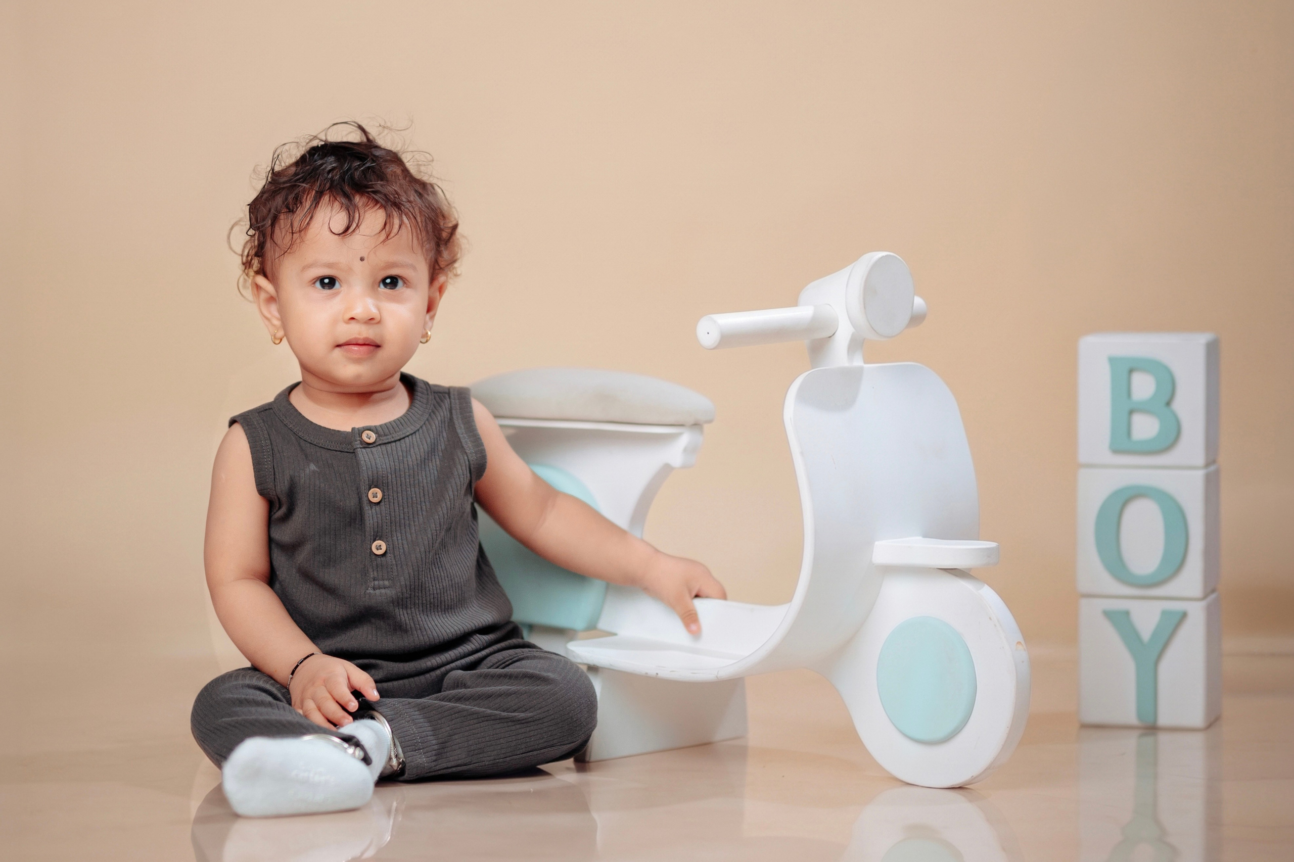 Toddler boy posing next to a white scooter prop and alphabet blocks in Butwal Nepal.
