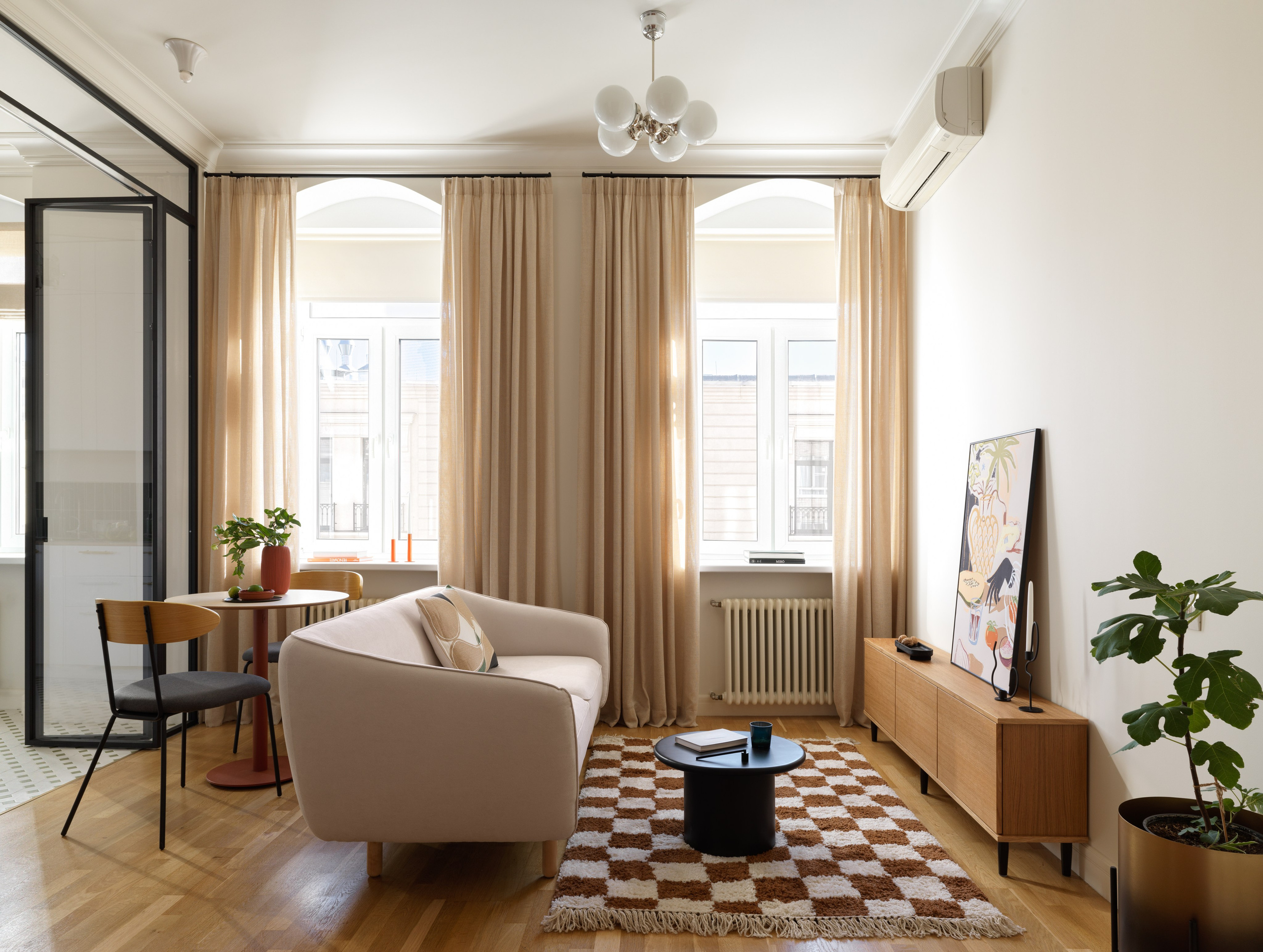 Просторная гостиная, разделённая стеклянной перегородкой, с арочными окнами и световым окном из стеклоблоков.