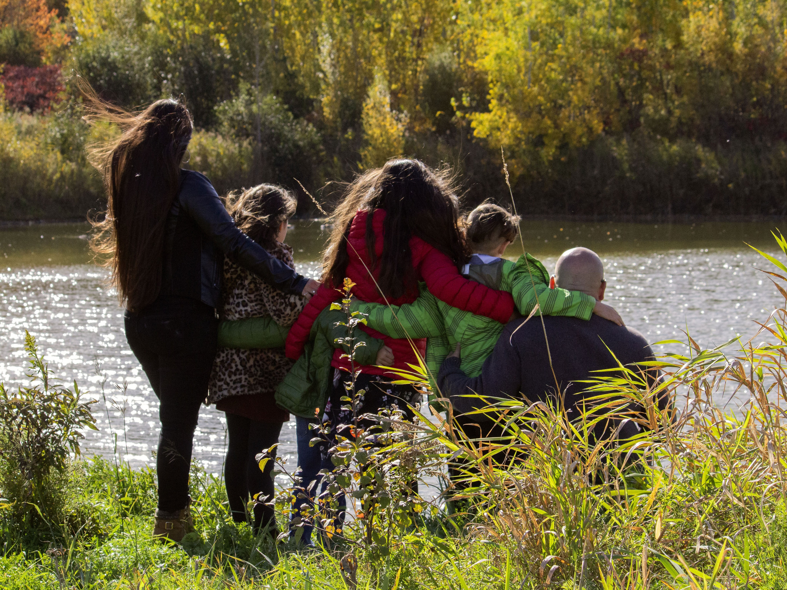 Candid family moment by the water during a fall photoshoot in Calgary