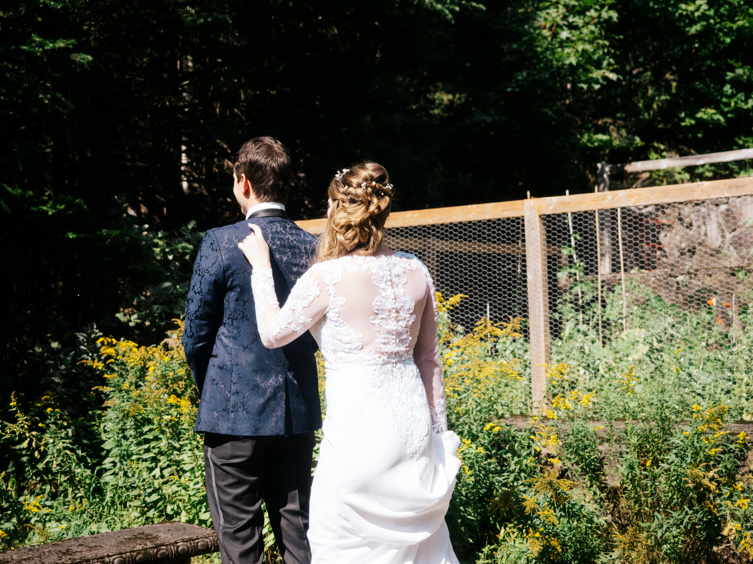 The bride is tapping on the grooms shoulder for the first look.