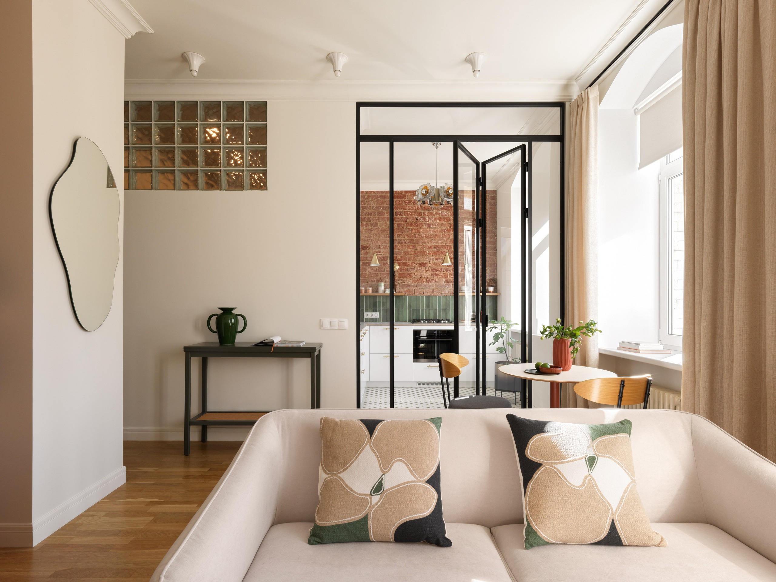 Просторная гостиная с арочными окнами и стеклянной перегородкой.