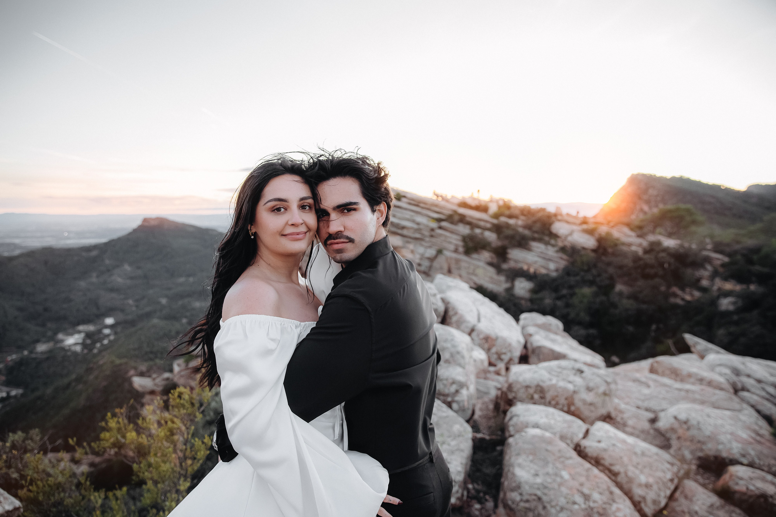 Couple embracing beside pale rocks at sunset during a mountain photoshoot near Valencia.