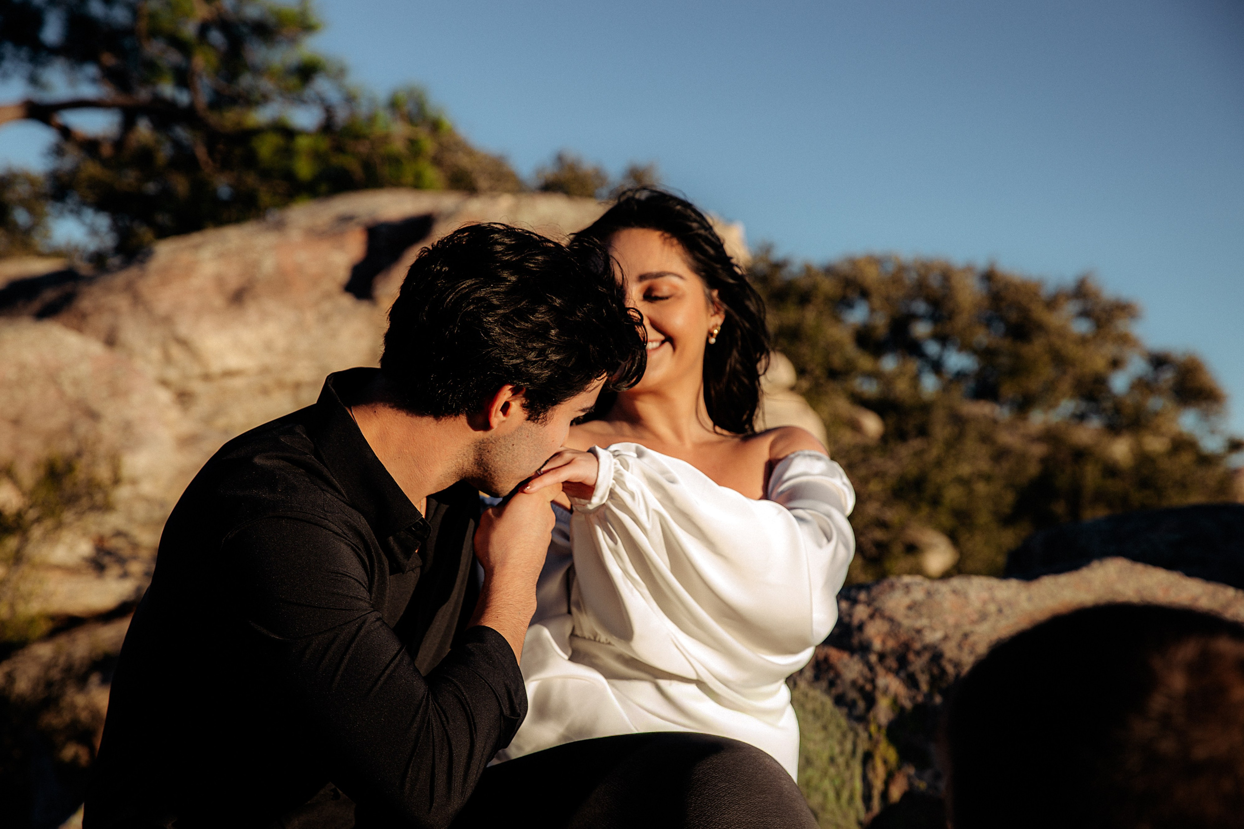 Man kissing his partner’s hand as she smiles during a mountain photoshoot near Valencia.
