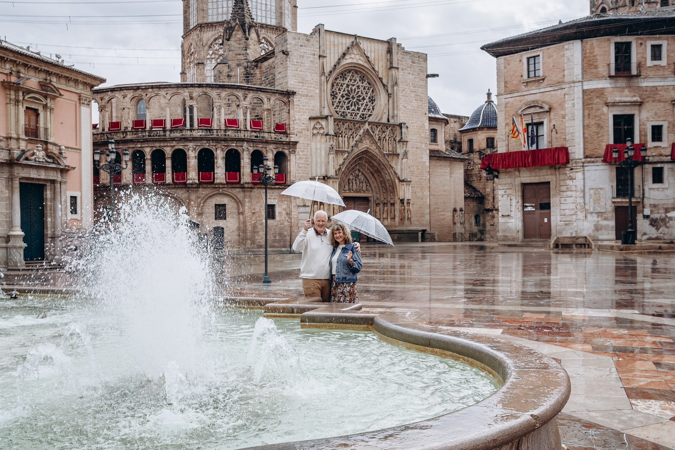 Фотосессия пары на площади Пласа-де-ла-Вирхен в Старом городе Валенсии с исторической архитектурой и деталями собора.