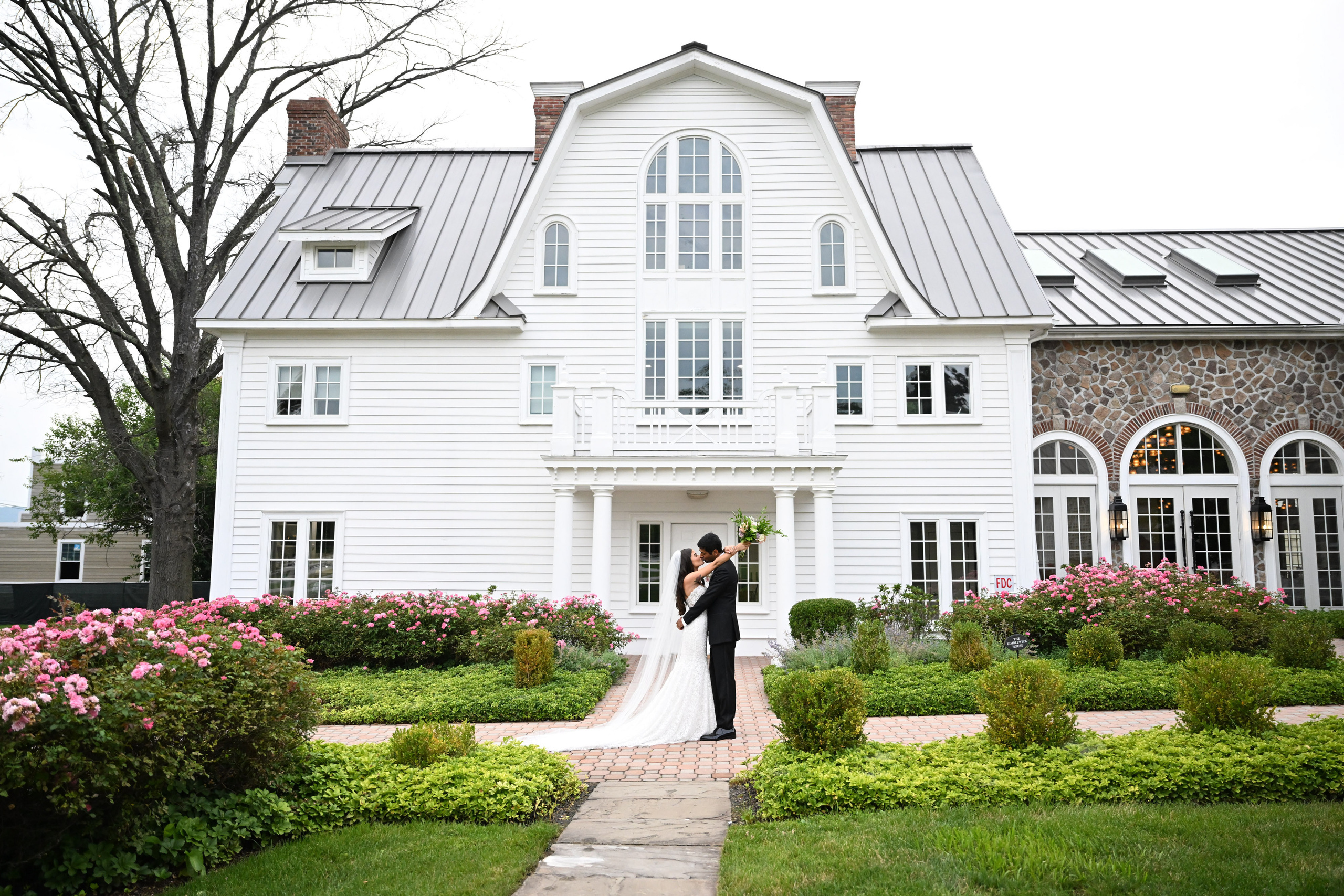 a bride and groom standing in front of a white house