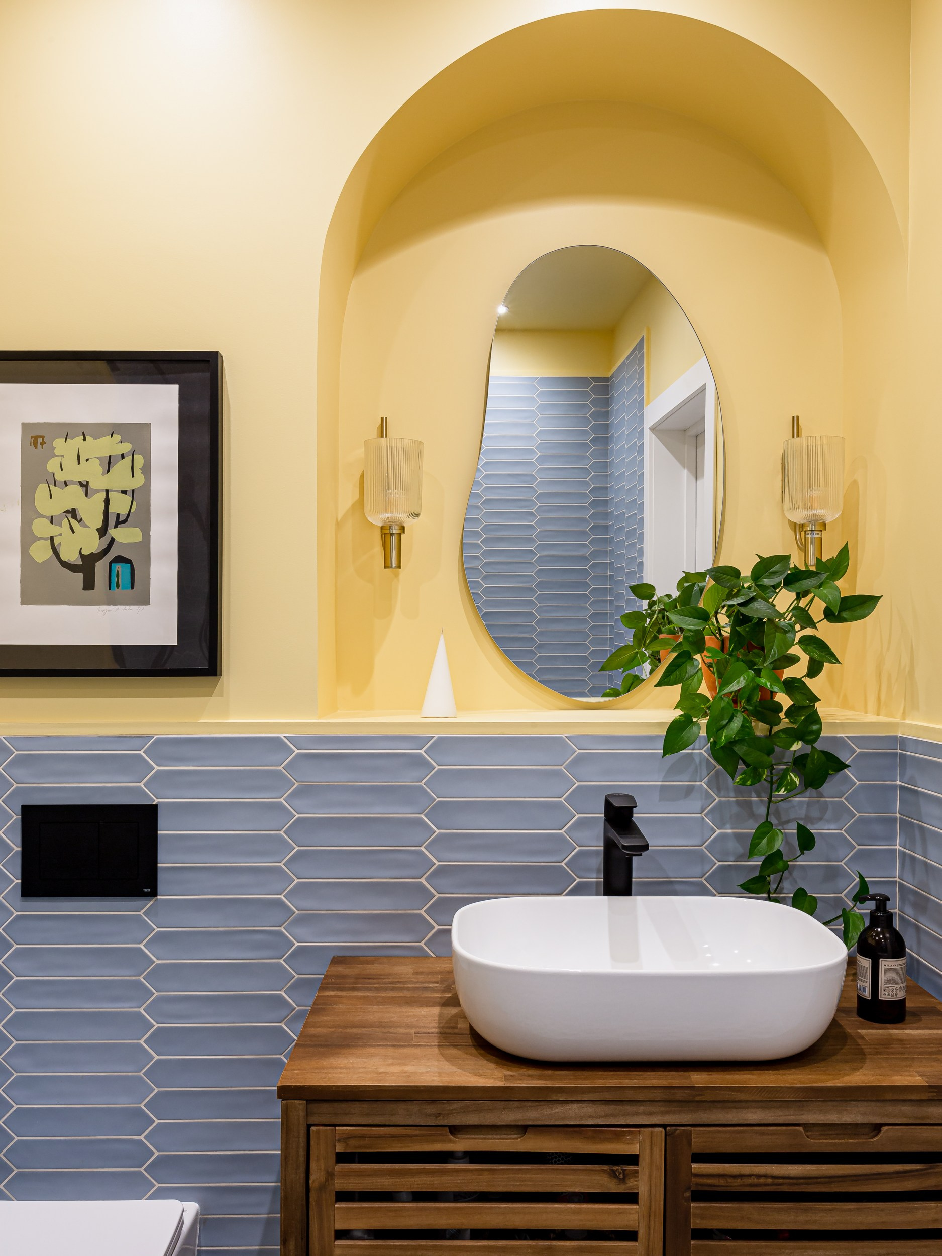 Ванная с деревянной тумбой и накладной раковиной на фоне желтых стен