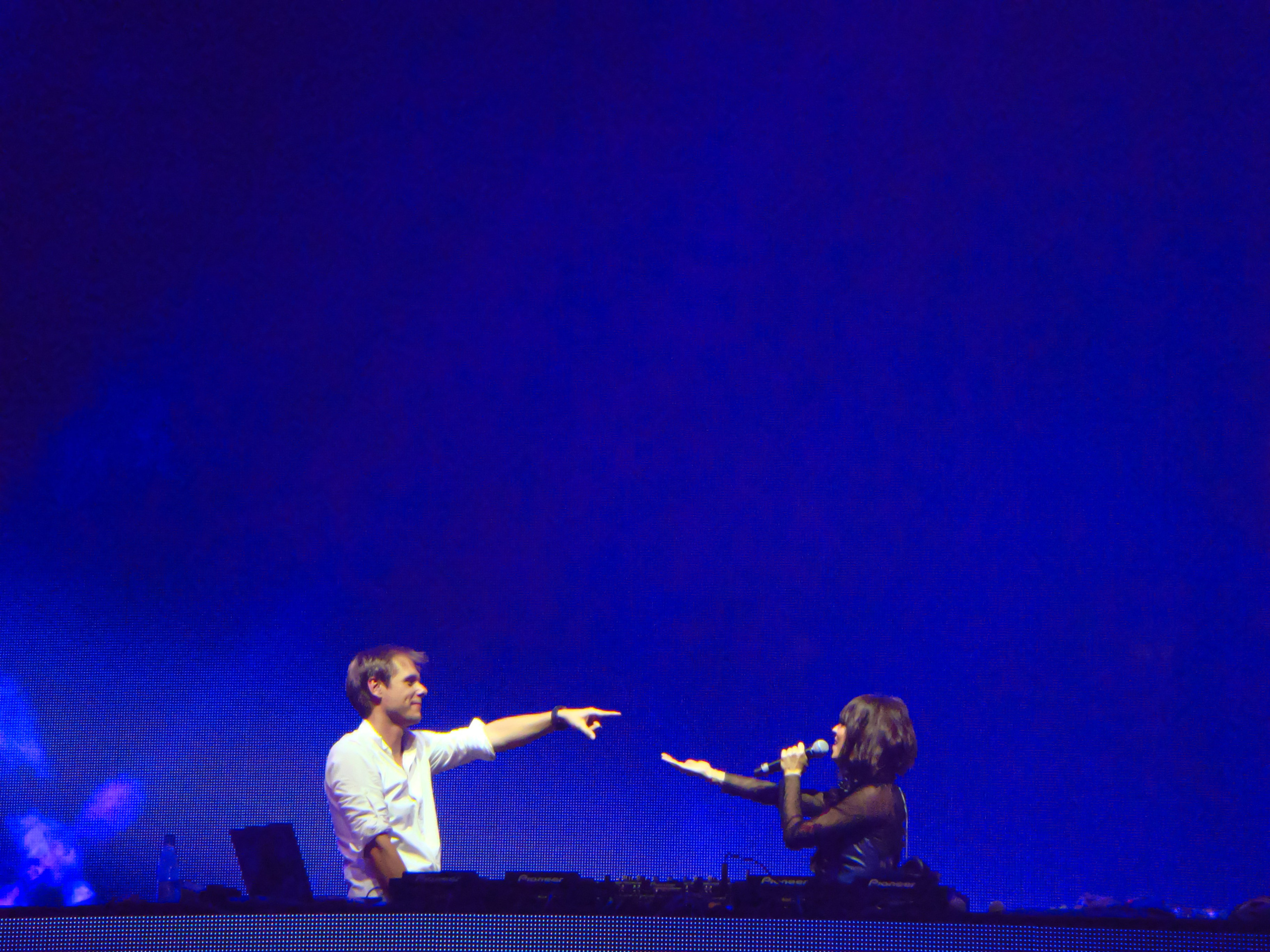 Armin van Buuren performing on stage with a singer at an electronic music festival, creating a dynamic atmosphere
