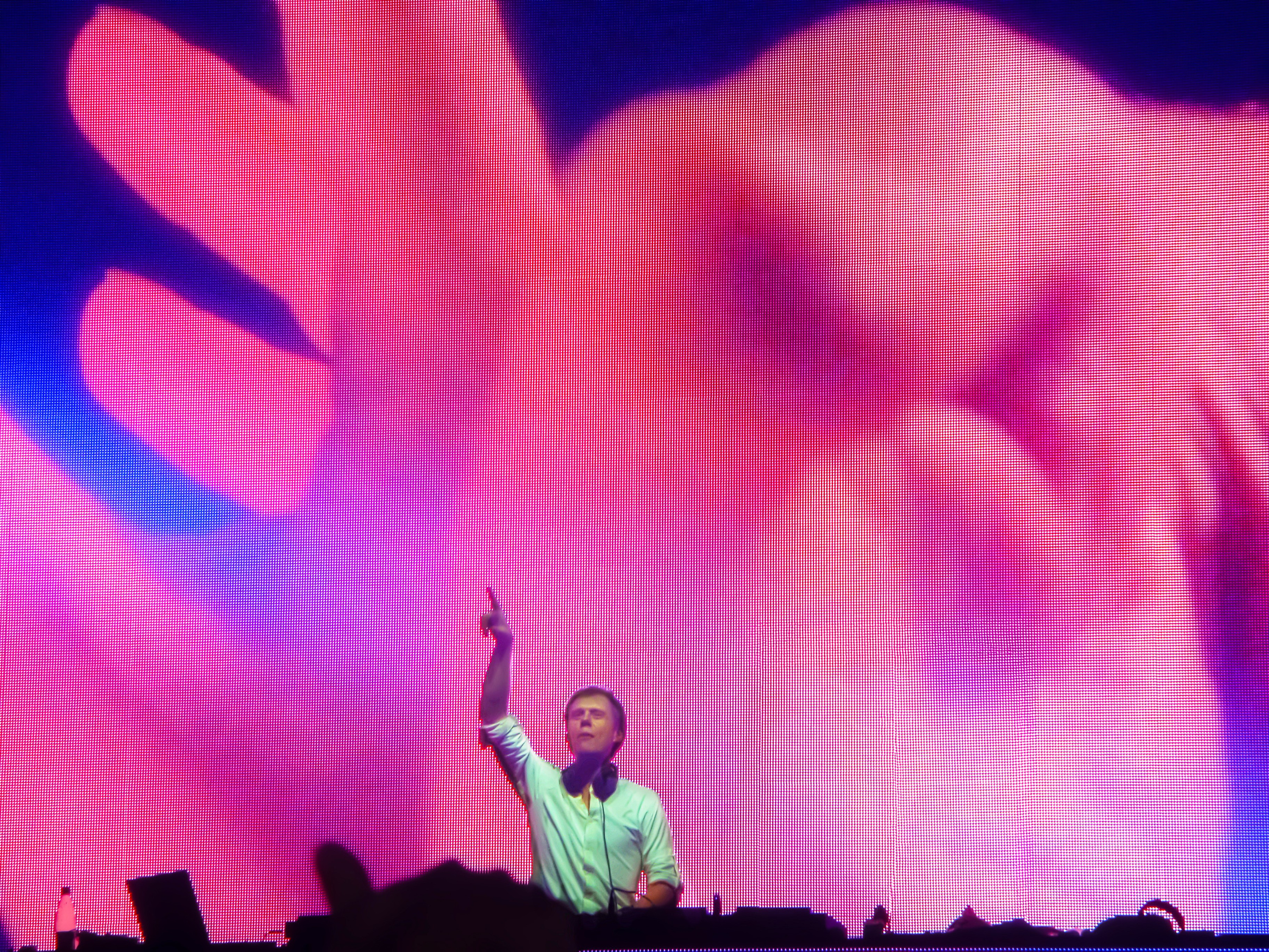 Armin van Buuren performing at a music festival behind the DJ booth, creating an electrifying atmosphere