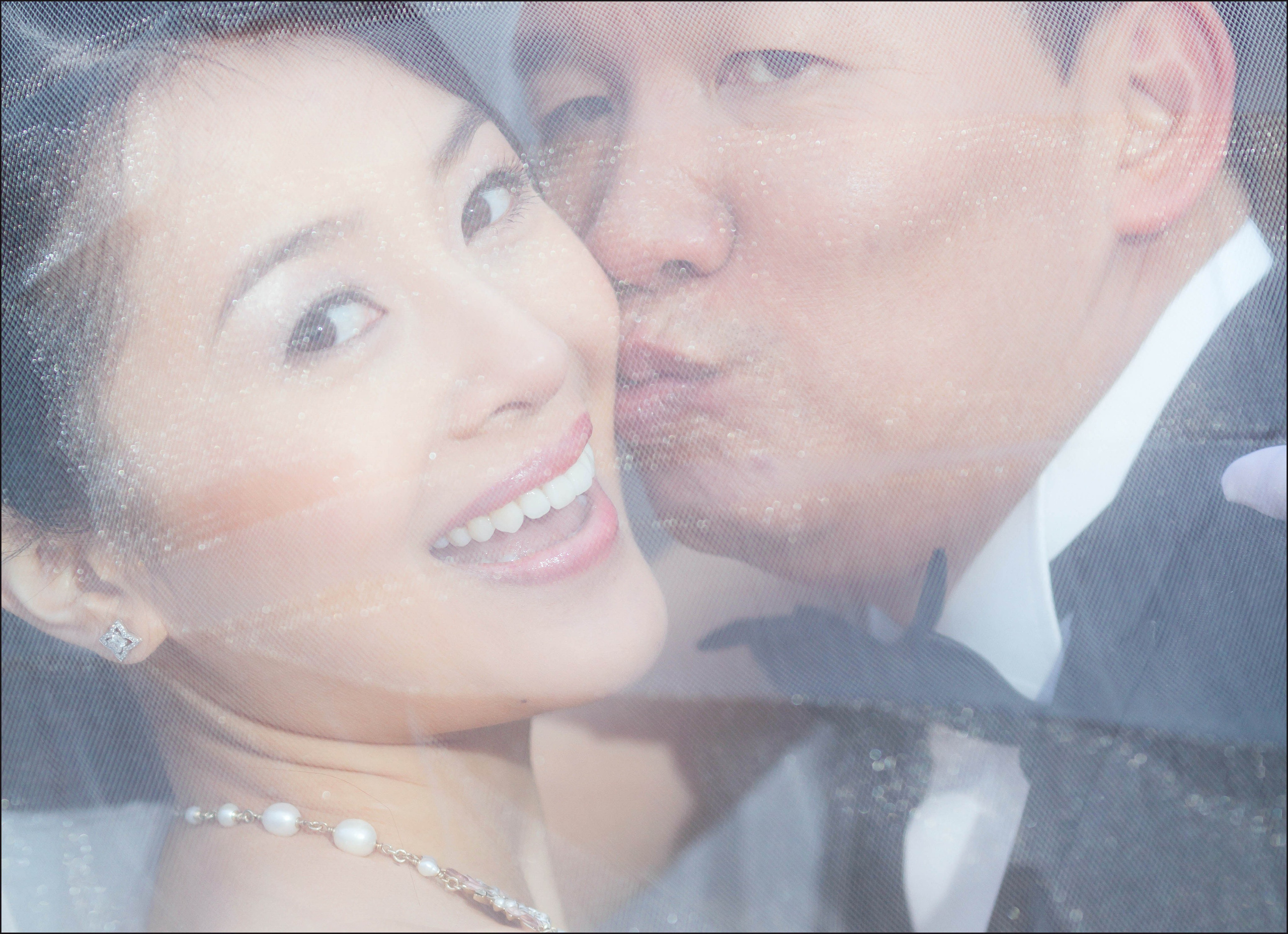 CY kisses Helen on the cheek as they look toward the camera during their winter pre-wedding in Prague.