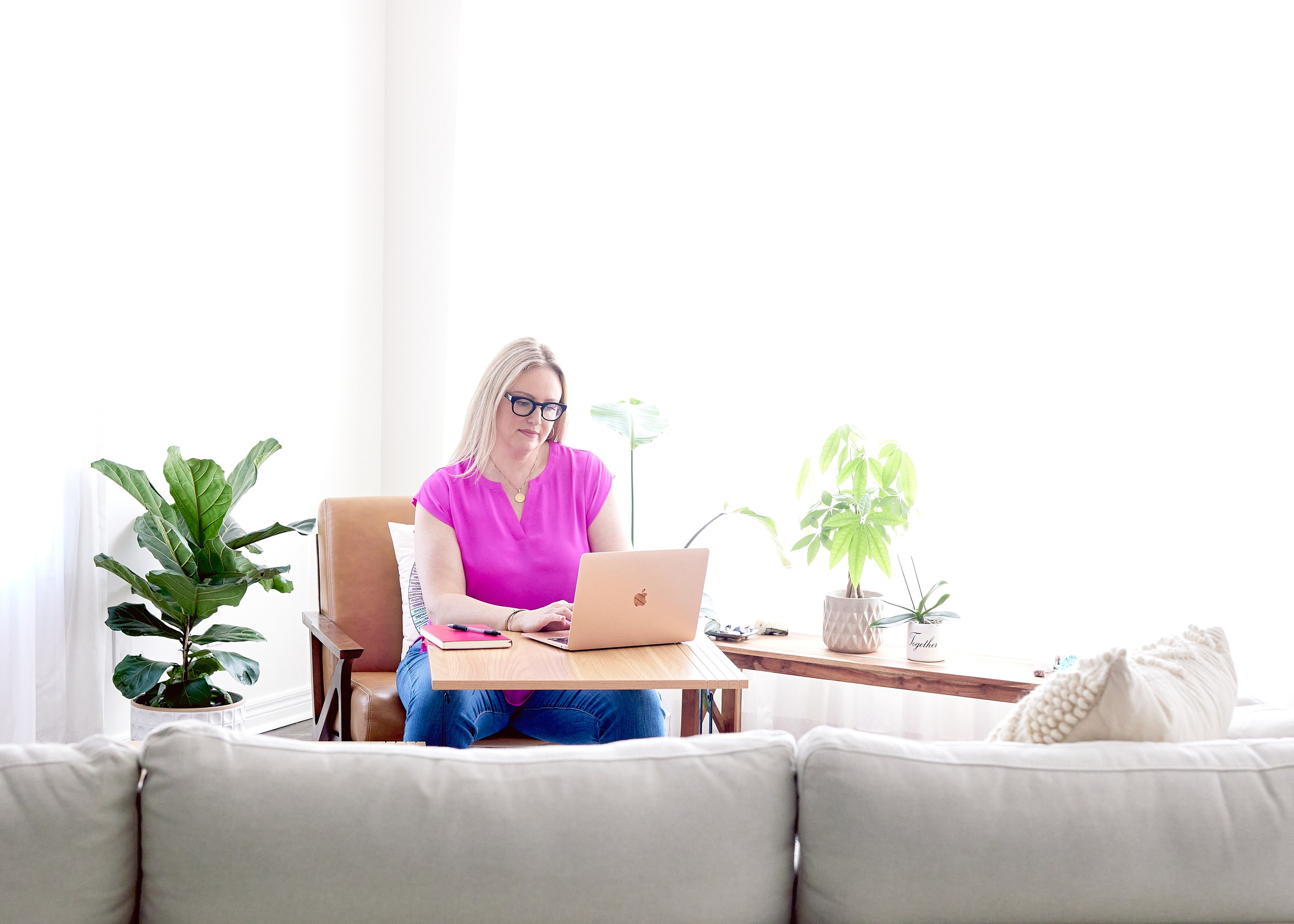 WOMAN IN PINK SITTING ON CHAIR FACING A COUCH WITH HER CLIENTS