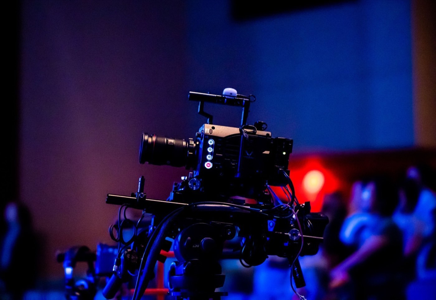 Professional video camera rig positioned in front of a seated event audience