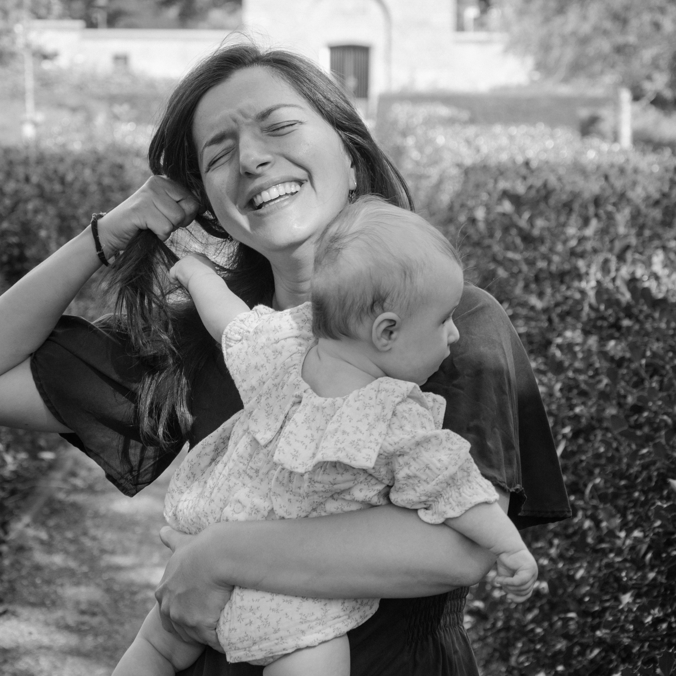 Family photography: a mother and her newborn pulling her hair. Shot in natural light in Amsterdam. 