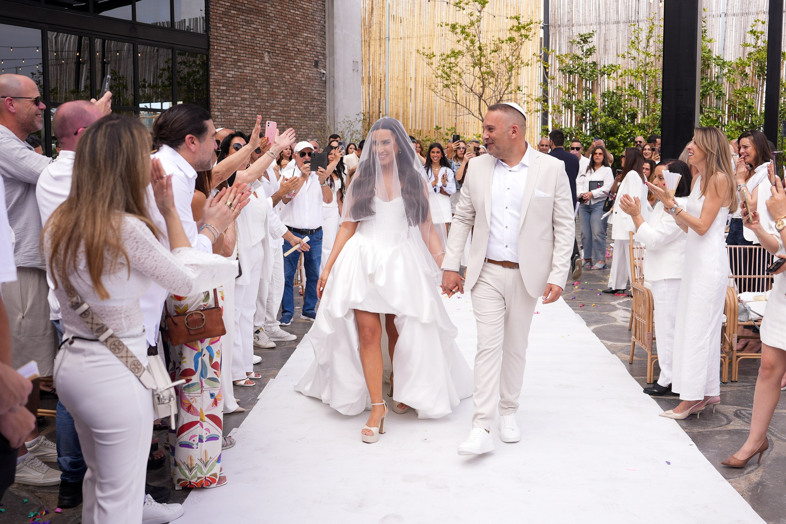 Bride Shani and groom David walking down the aisle during their wedding ceremony at Artista Event Garden in Hadera, Israel