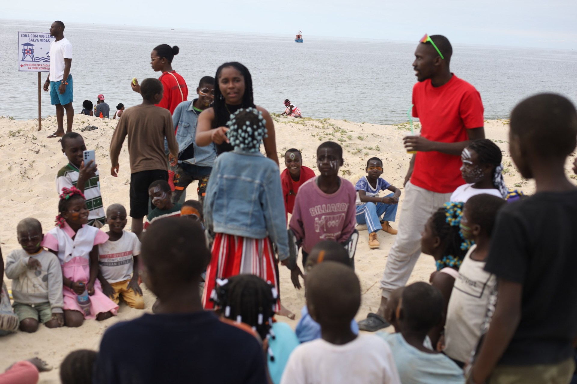 Crianças e participantes reunidos na praia durante o Festival Elefantes Bay
