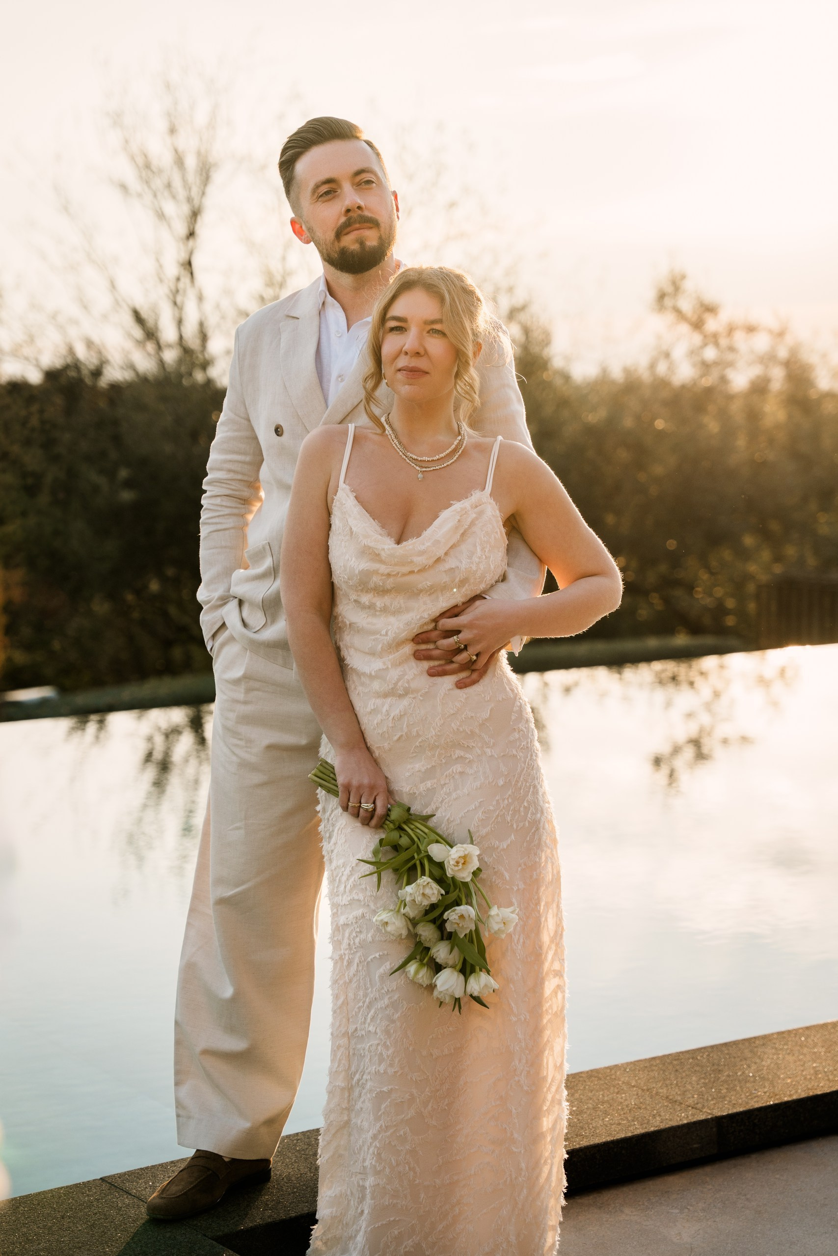 Mladenci pored bazena u zlatnom satu tokom fotografisanja.
