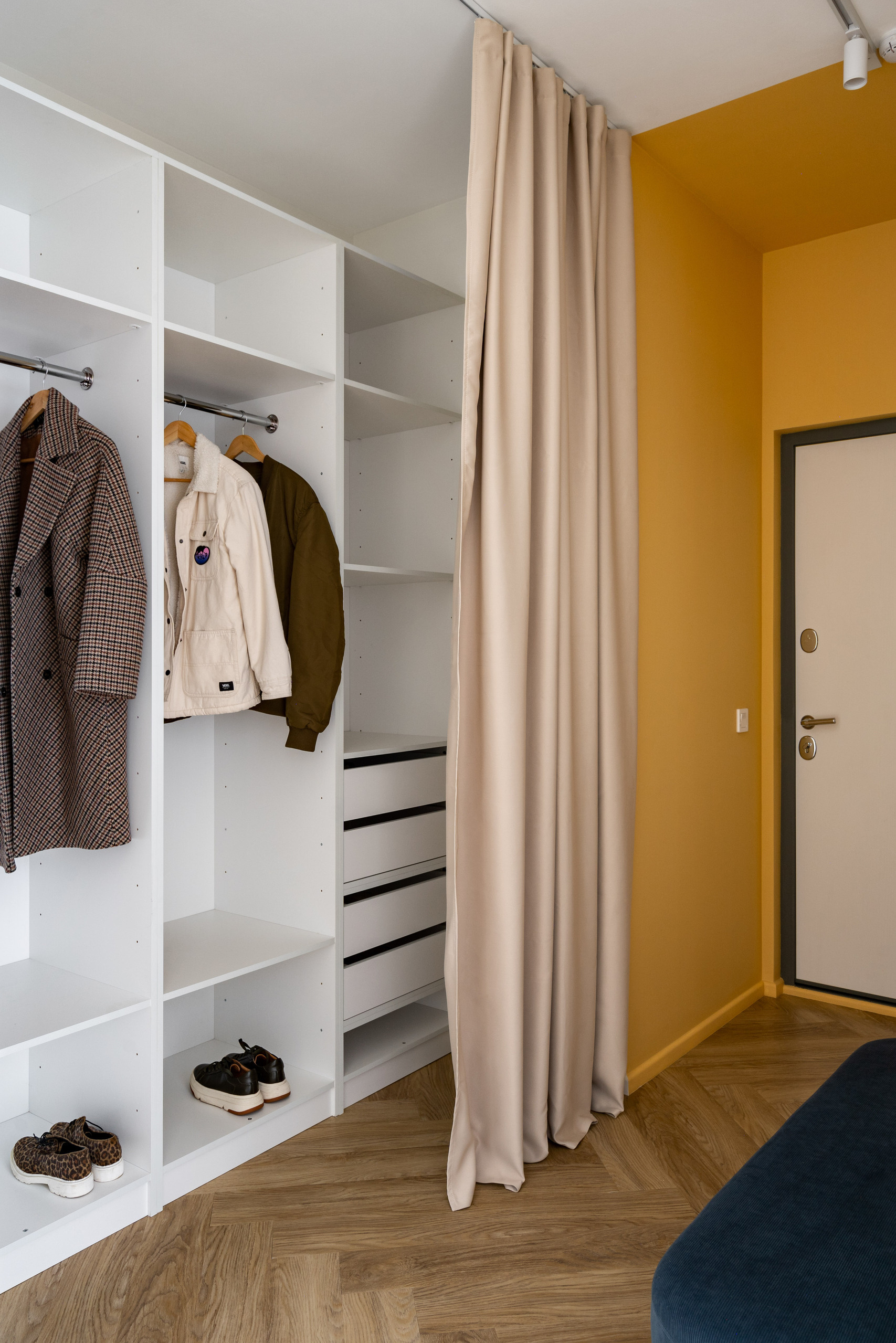 Прихожая в стиле минимализм с зеркалом, пуфом и шкафом для хранения одежды.