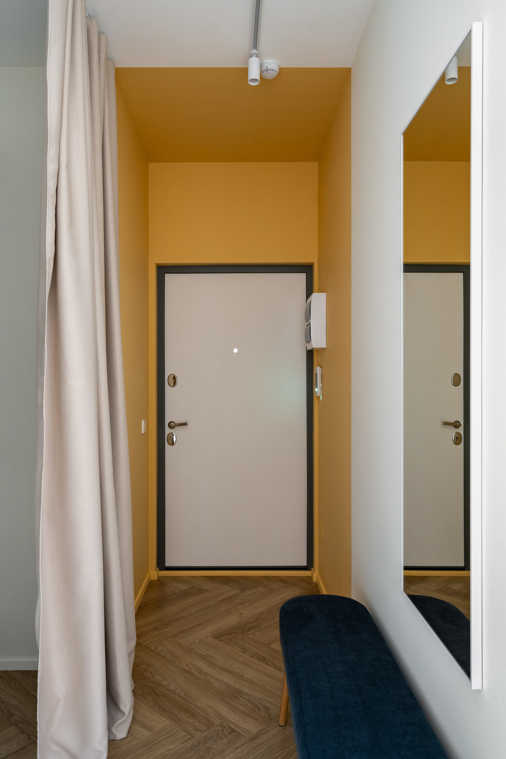 Прихожая со шкафом, зеркалом и пуфом для обувания.