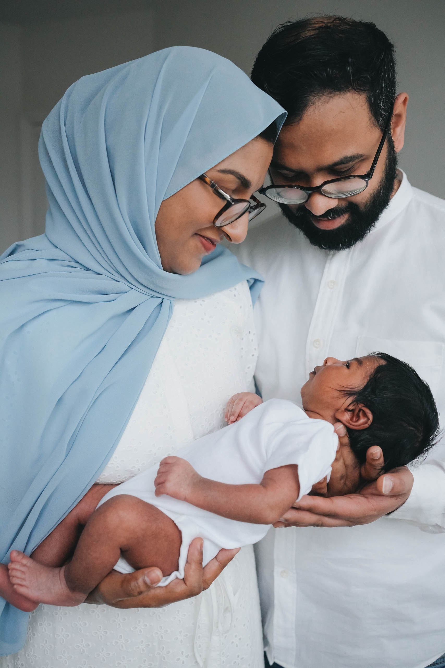Parents holding their newborn baby during a calm lifestyle newborn photography session at home in Solihull