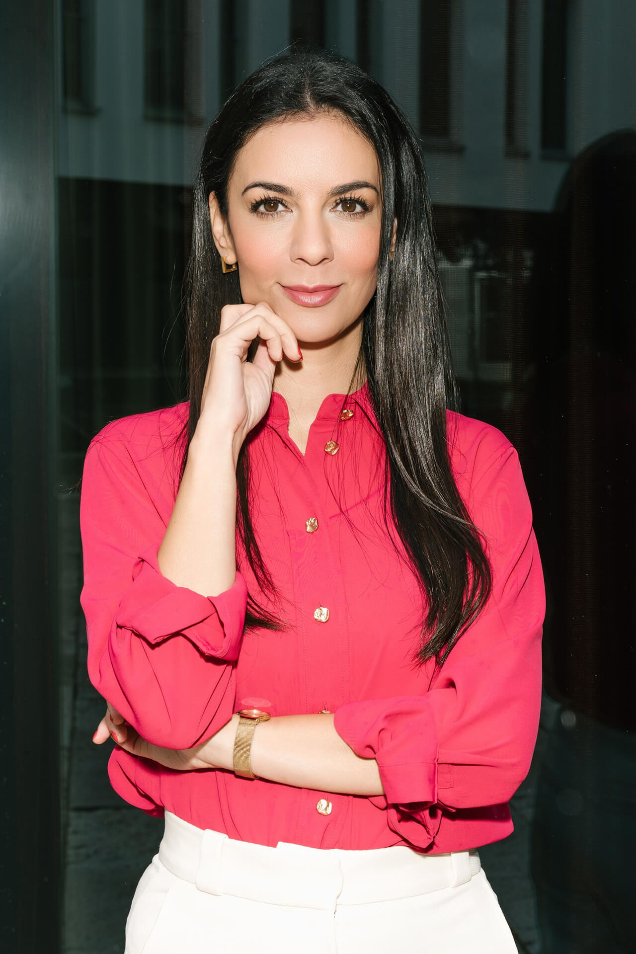 Professionelles Porträt einer Frau in leuchtender Bluse, lockere Pose mit Hand am Gesicht (moderner Corporate-Stil)