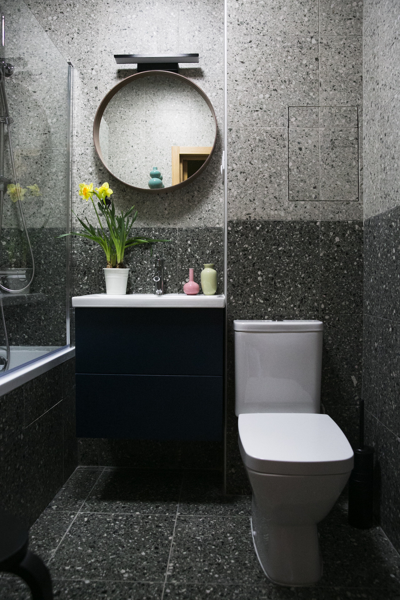 Светлая ванная комната с душем и яркими акцентами.