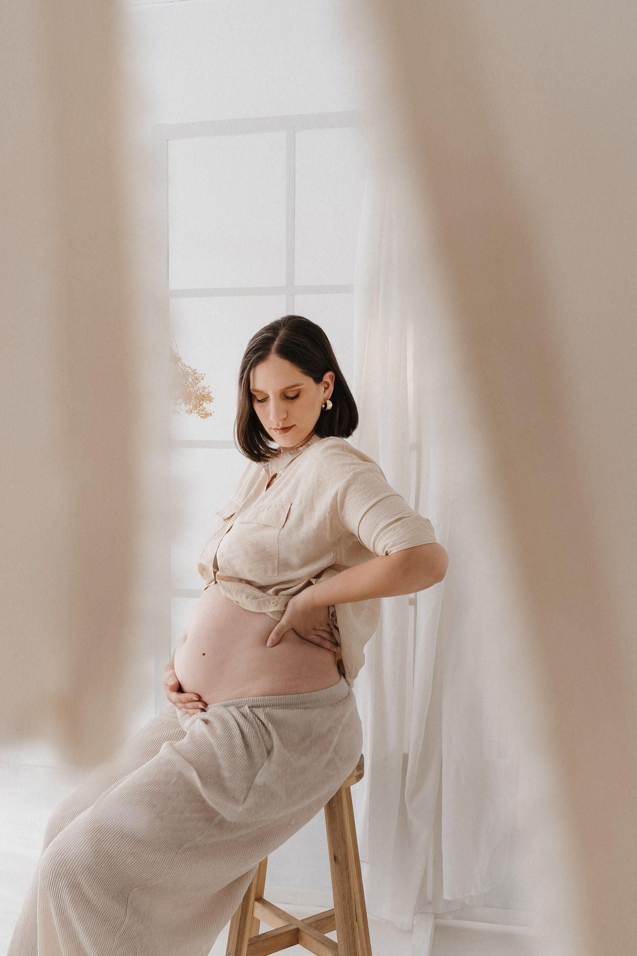 studijski portret trudnice koja gleda u stomak