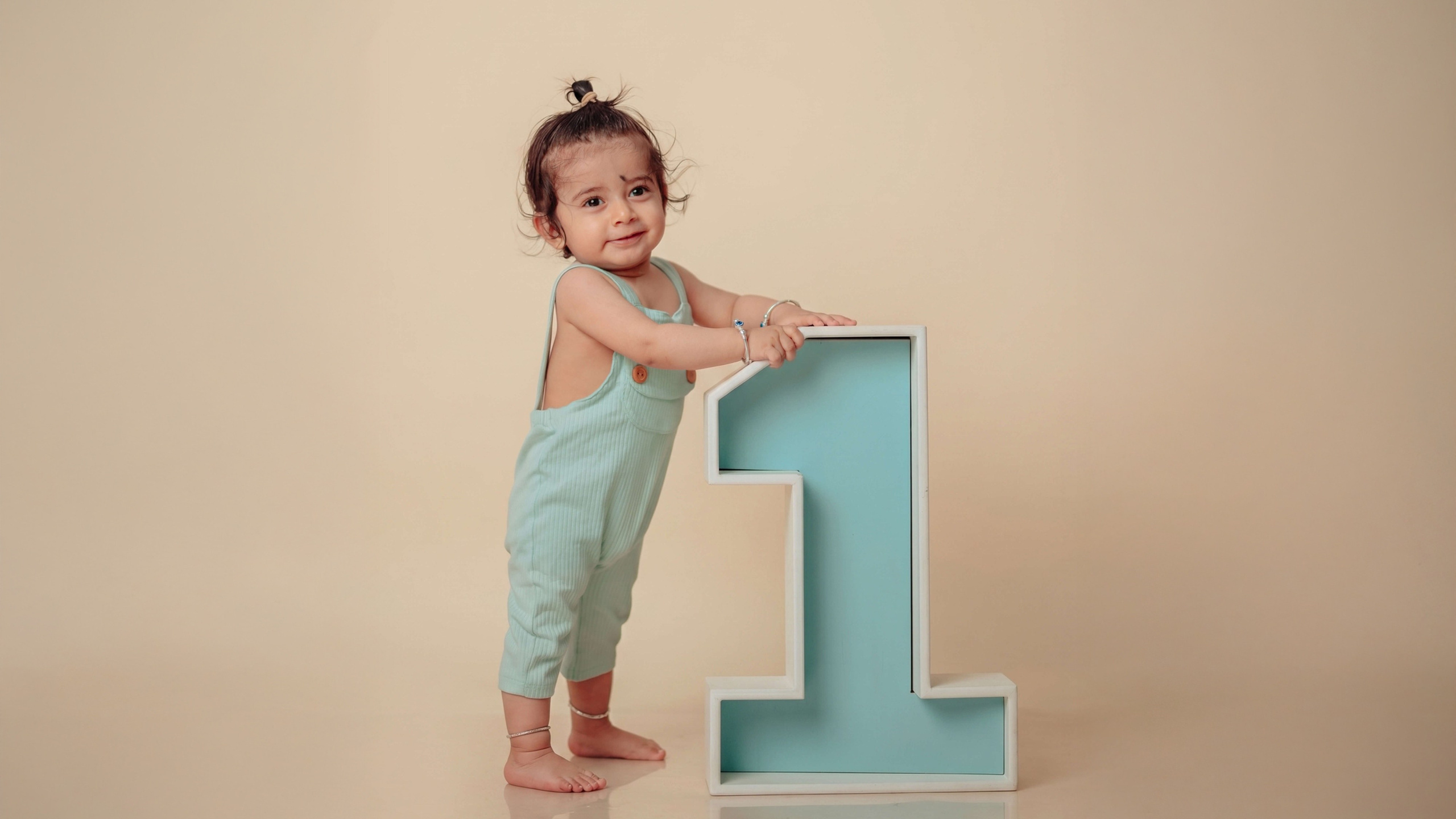 One-year-old baby standing with a large blue number one milestone prop. Butwal Baby Photoshoot.