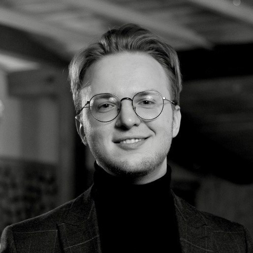 Portrait of Dmitrii Shmatov wearing glasses and a turtleneck, in black and white