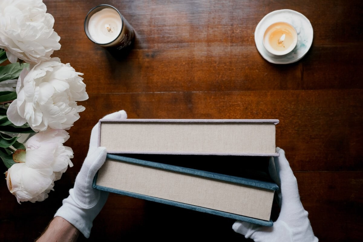 Wedding album held with gloves above wooden table and flowers