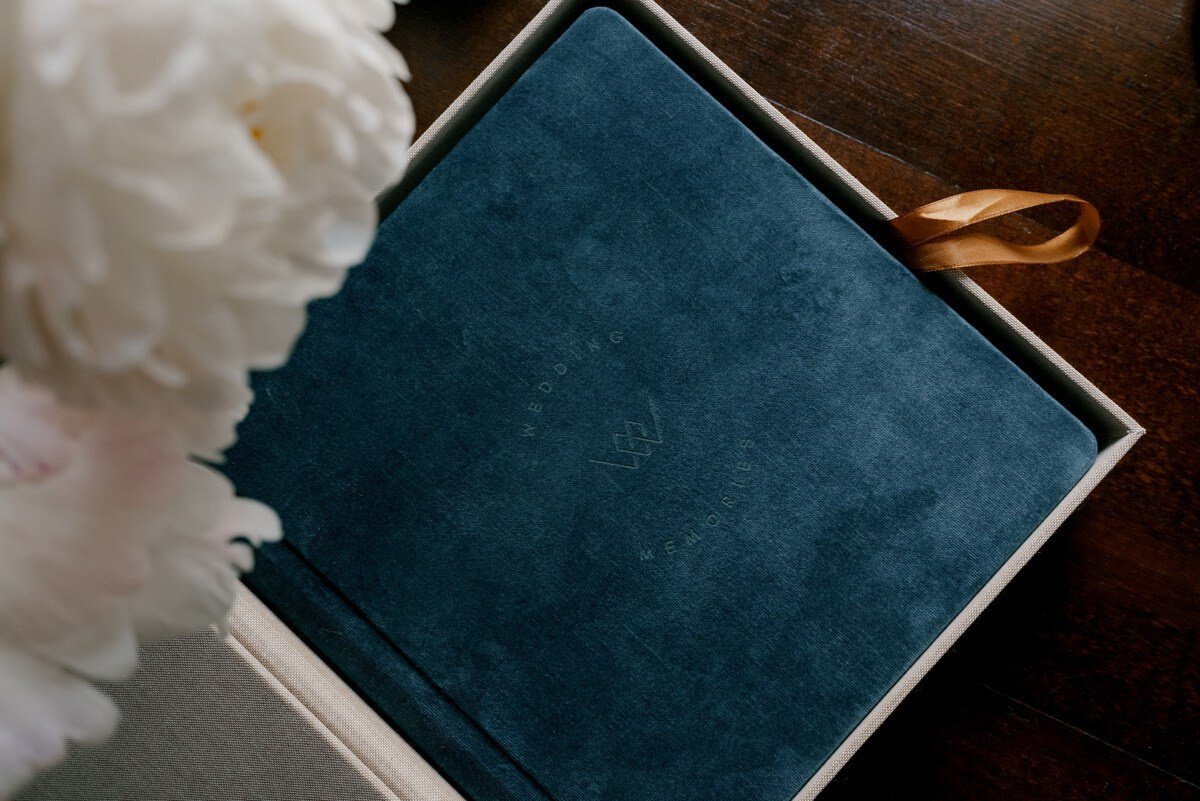 Luxury wedding album cover with ribbon placed beside white flowers