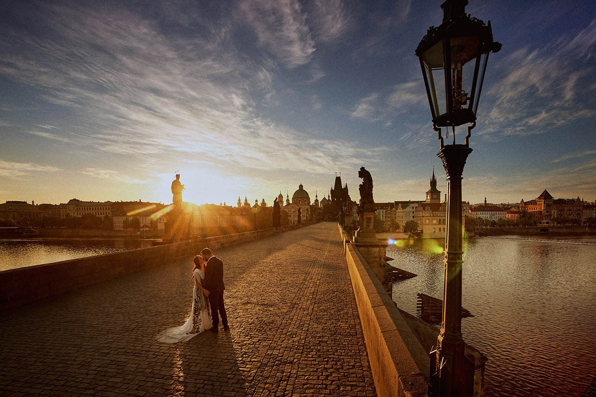An American couple embraces alone atop the Charles Bridge at sunrise during their engagement portrait session in Prague. 