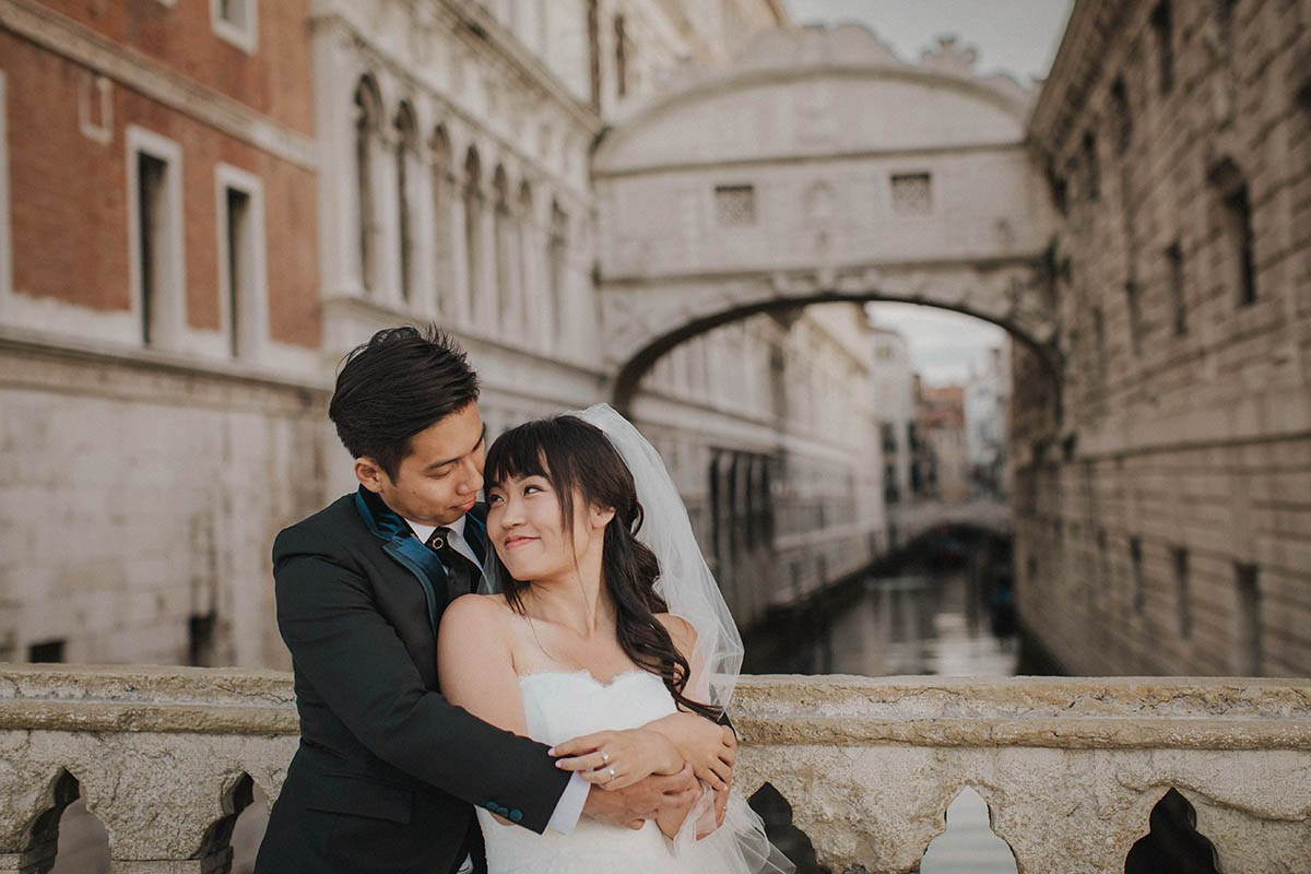 Young newlyweds embrace overlooking the canal where the Bridge of Sighs lies in Venice - Kurt Vinion Photography