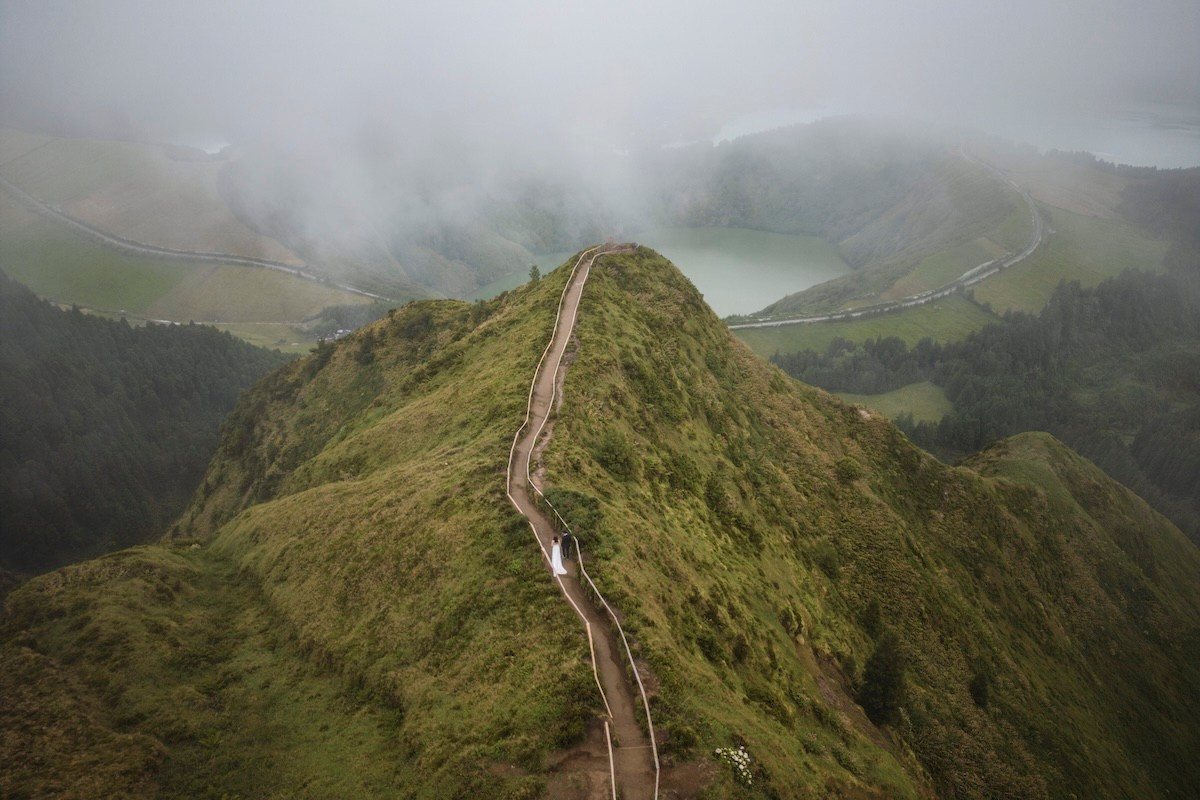 Newlyweds walking along a volcanic crater ridge in the Azores during their destination wedding in Portugal