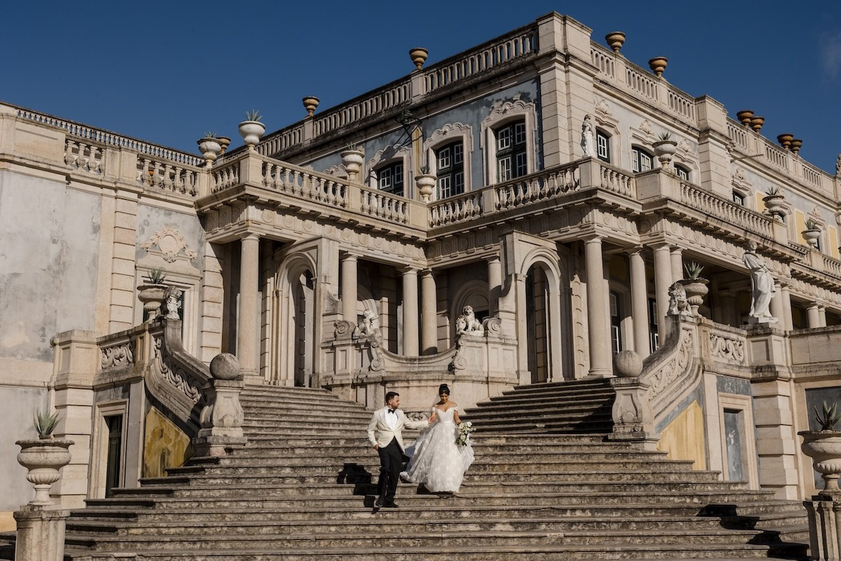 Bride and groom descending the grand staircase of a historic palace during their destination wedding in Portugal