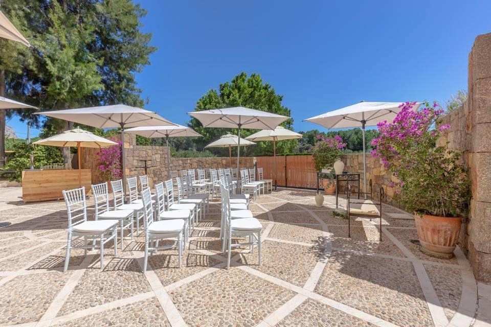 Outdoor ceremony terrace at Dénia Marriott La Sella Golf Resort & Spa, with white chairs, parasols and bougainvillea.