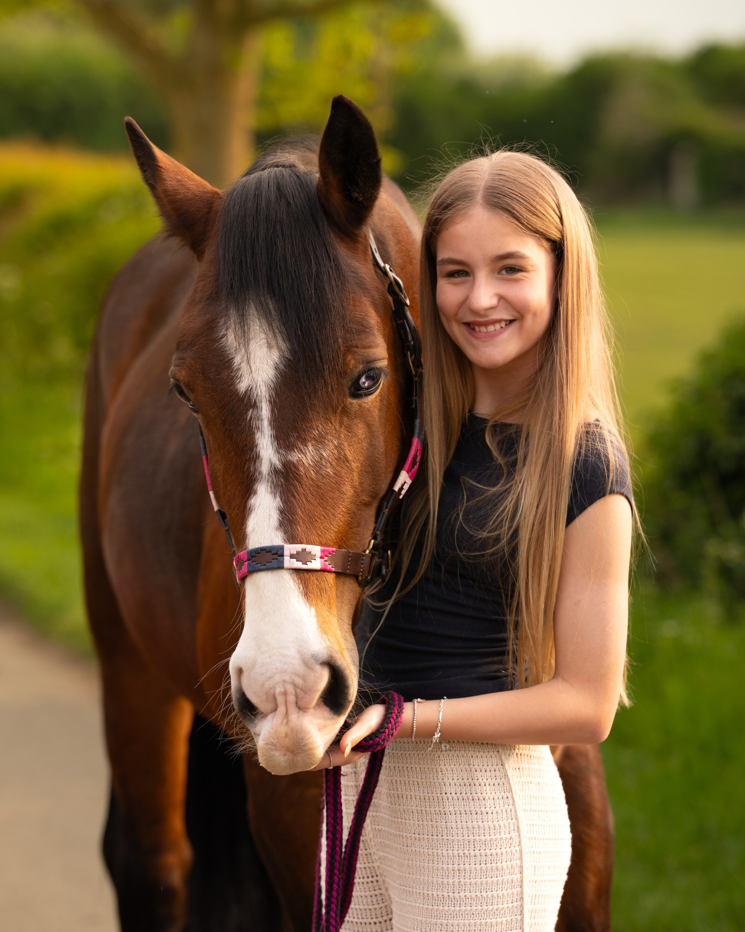 Teen girl holding horse’s halter during soft evening light equestrian portrait