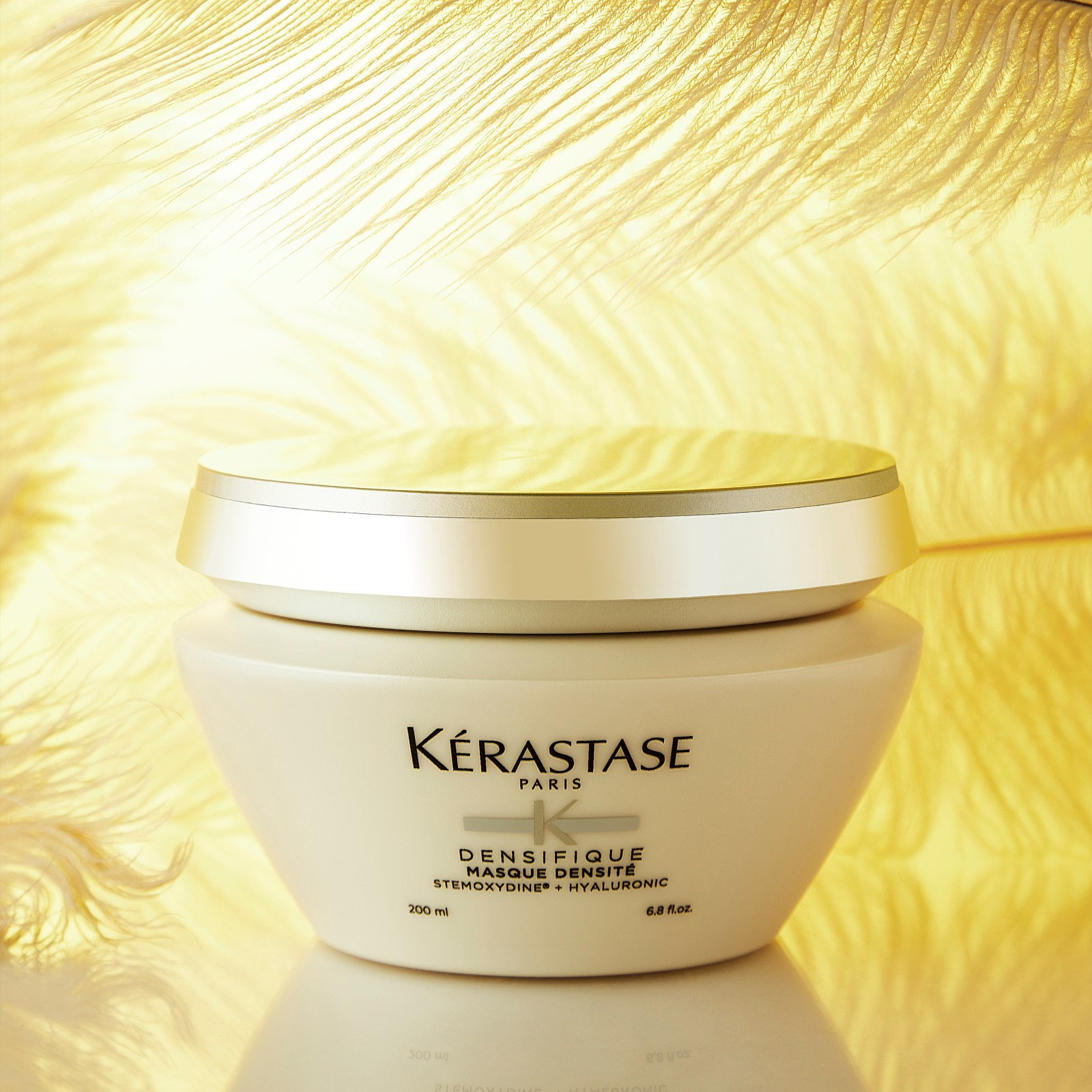 Photographer Roman Djuzev - Close-up of Kerastase Densifique Masque Densite on a light yellow background with big large flying feathers.