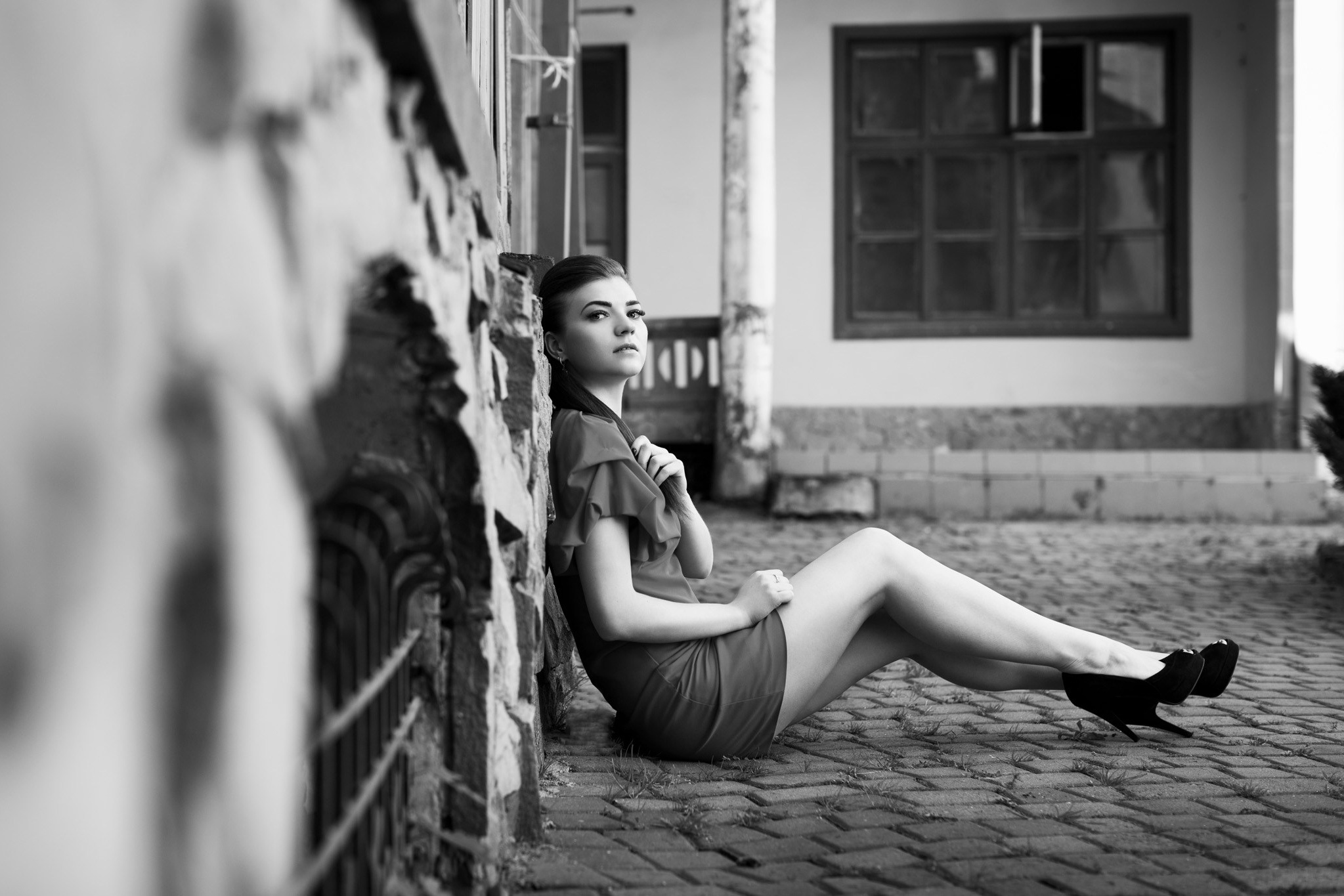 чорно-біла фотографія, дівчина сидить на брущатці і дивиться в кадр